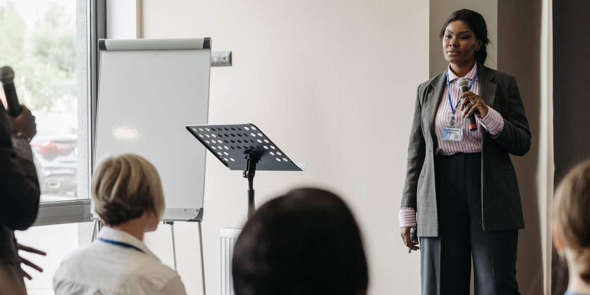A confident professional presenting in a bright, modern meeting room.