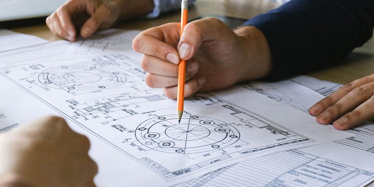 A team huddles around a table with blueprints, symbolizing the careful planning and pilot programs needed for AI implementation.