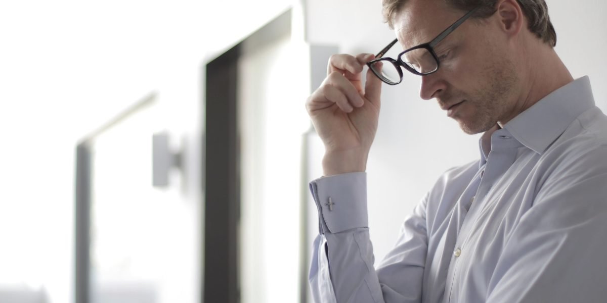 A person appears deep in thought, surrounded by various papers or digital screens, symbolizing the challenge of information overload.