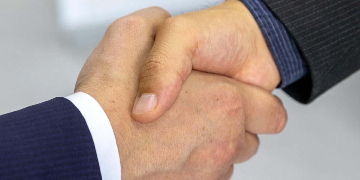 Two professionals shaking hands, symbolizing a finalized agreement and trust.